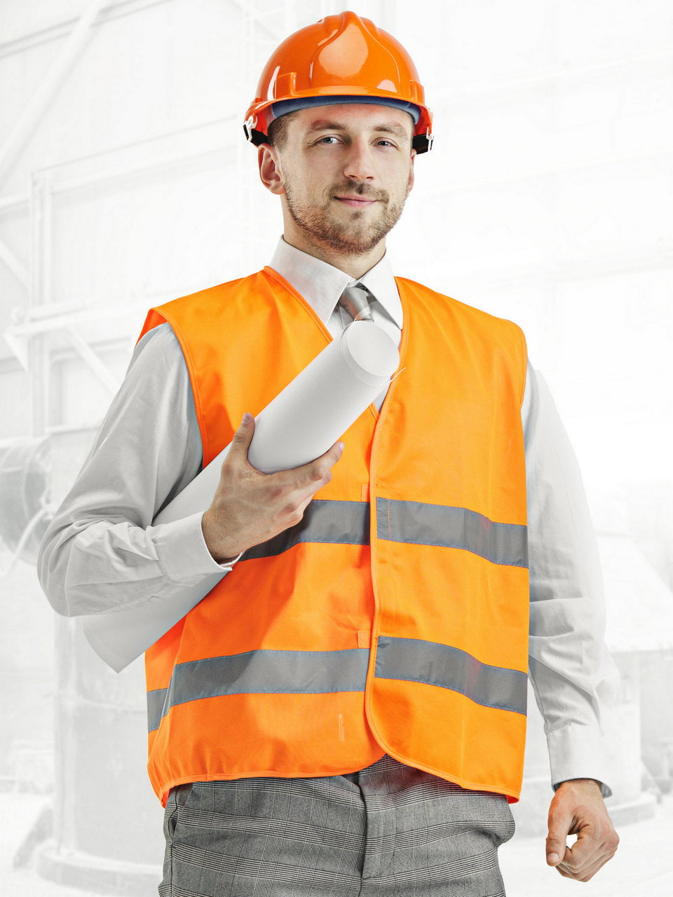 The builder in a construction vest and orange helmet standing against industrial background. Safety specialist, engineer, industry, architecture, manager, occupation, businessman, job concept